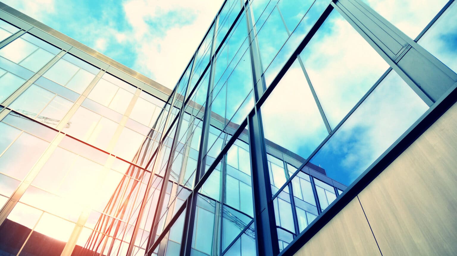 Modern glass building reflecting sky and clouds, perfect for a Home Hero Slider background.