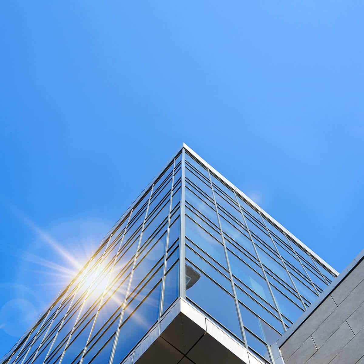 Modern glass building gleams in sunlight, perfect for your Home Hero Slider background.